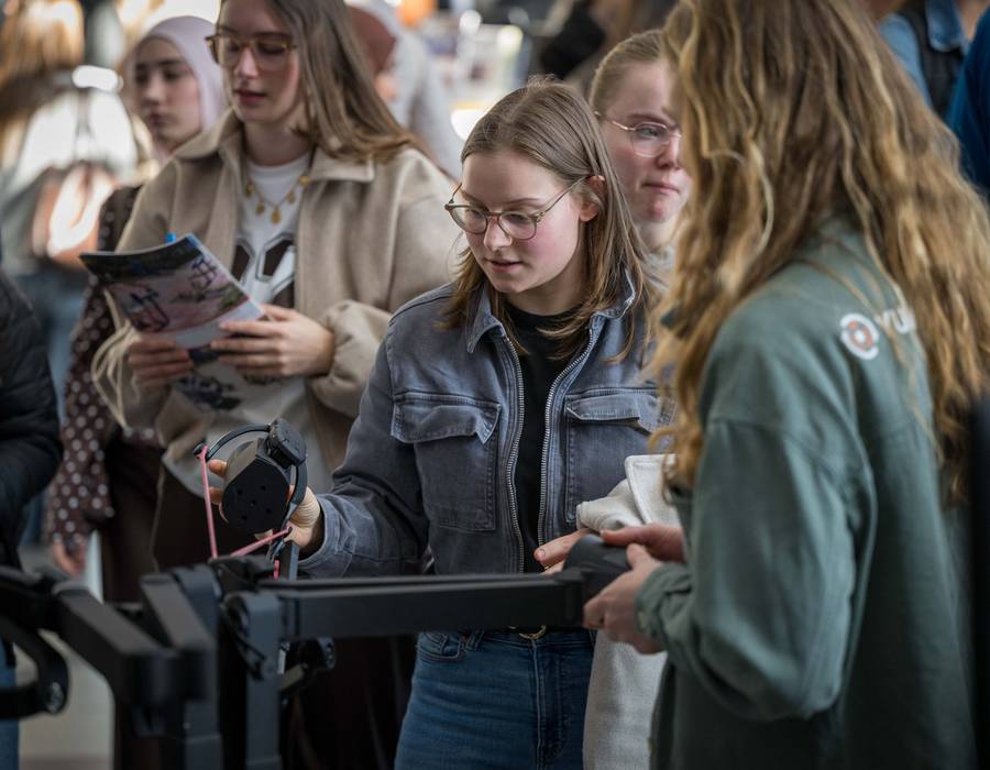 Groepje studenten bekijkt een demonstratie bij een stand