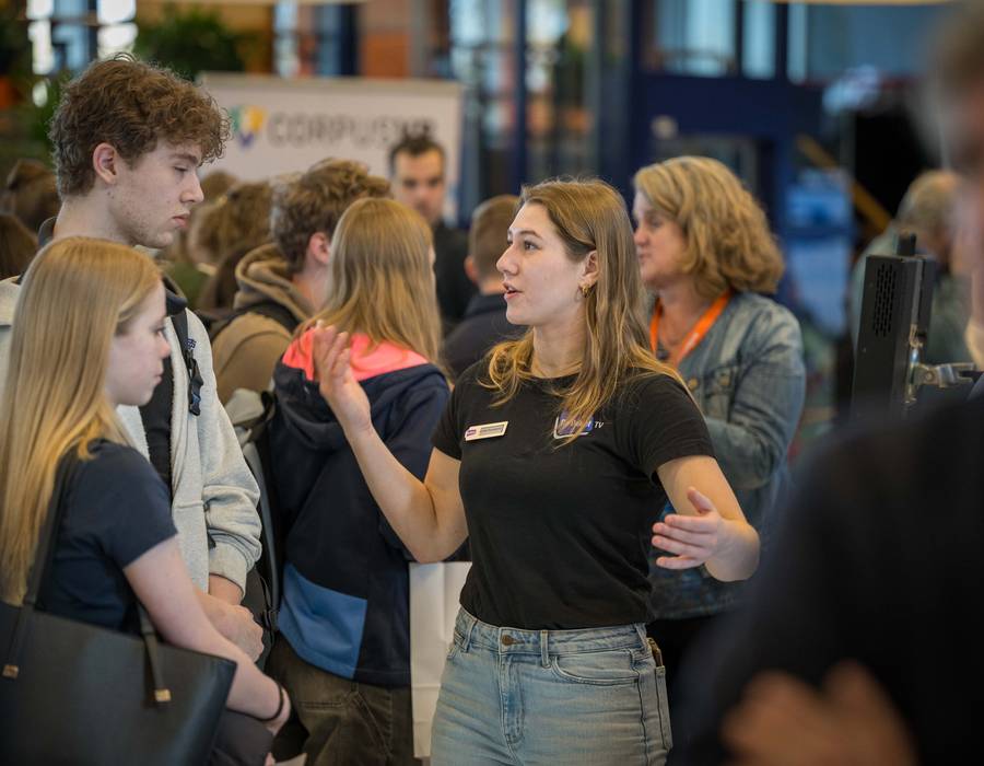 Standhouder in gesprek met twee scholieren